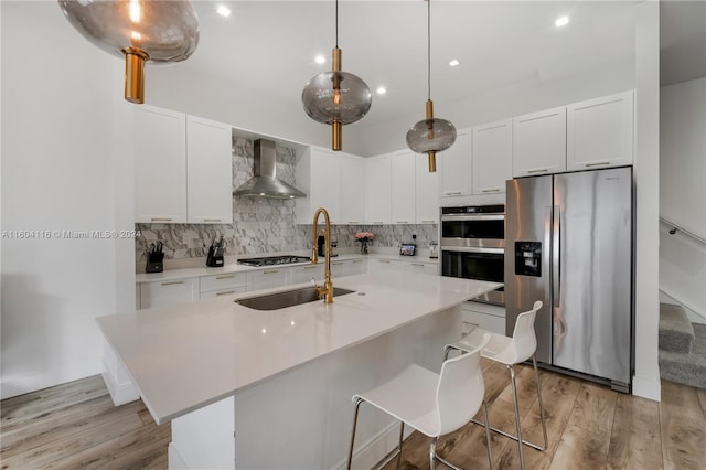 kitchen with light hardwood / wood-style flooring, wall chimney range hood, stainless steel appliances, and white cabinets