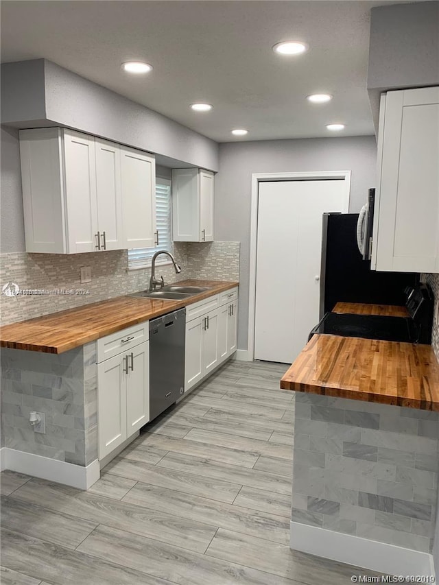 kitchen featuring tasteful backsplash, stainless steel appliances, wood counters, sink, and white cabinetry