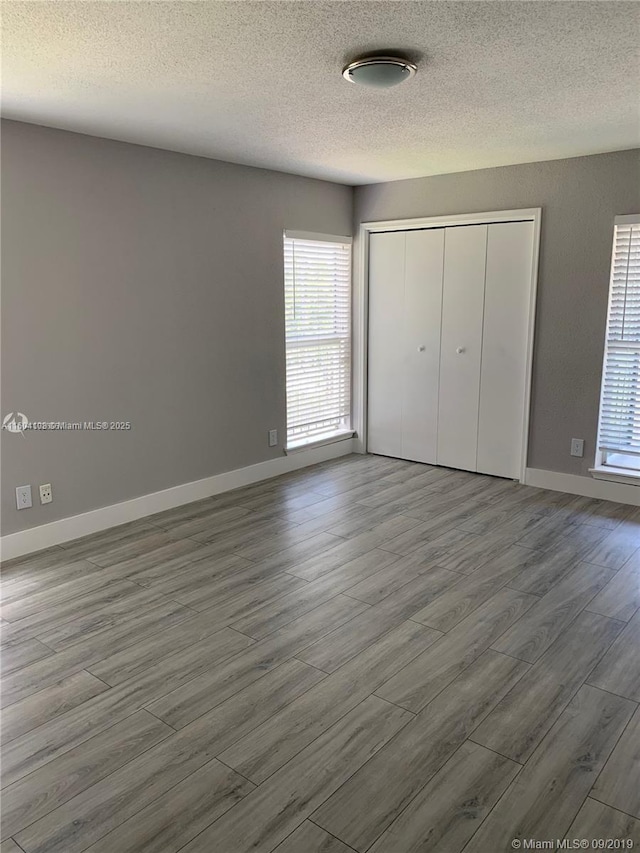 unfurnished bedroom with hardwood / wood-style flooring, a closet, and a textured ceiling