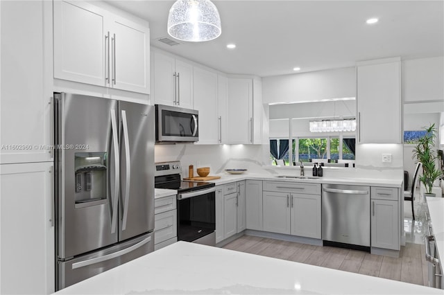 kitchen featuring light wood-type flooring, white cabinetry, light stone countertops, sink, and stainless steel appliances