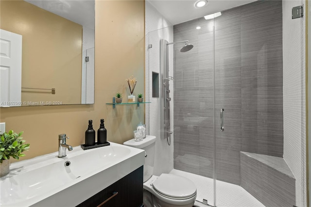 bathroom with toilet, a shower with door, and vanity