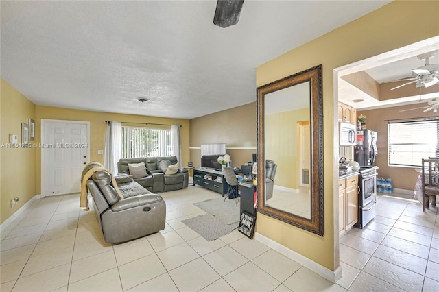 tiled living room featuring ceiling fan and a textured ceiling