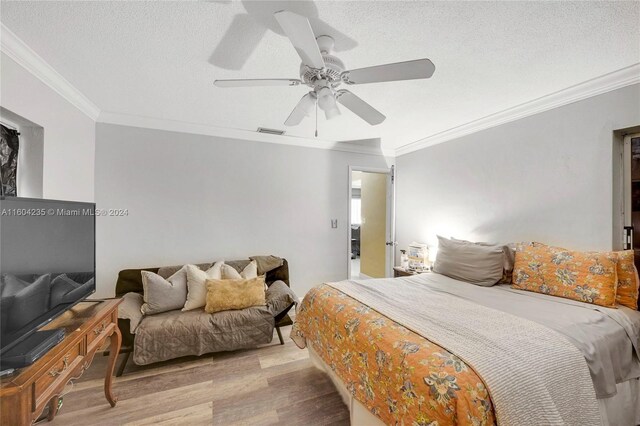 bedroom with a textured ceiling, light hardwood / wood-style flooring, ceiling fan, and ornamental molding