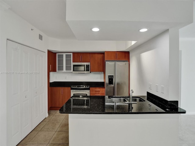 kitchen featuring kitchen peninsula, sink, appliances with stainless steel finishes, and dark stone counters