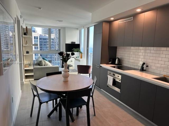 kitchen featuring black electric stovetop, oven, and tasteful backsplash