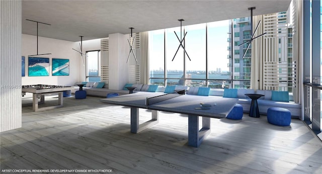 recreation room with hardwood / wood-style flooring, expansive windows, and a water view