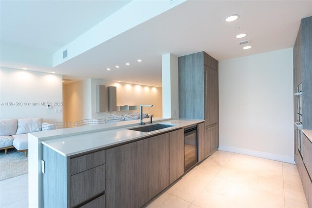 kitchen featuring oven, sink, kitchen peninsula, and light tile floors