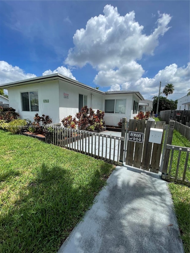 view of front of property featuring a front lawn, a fenced front yard, a gate, and stucco siding