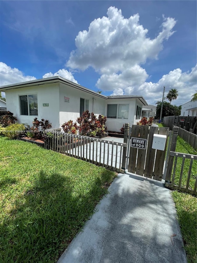 view of front facade with a fenced front yard, a front yard, a gate, and stucco siding