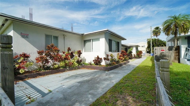 view of side of home featuring fence, a lawn, and stucco siding