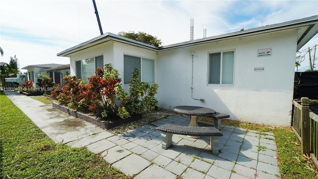 view of property exterior featuring a patio area, fence, and stucco siding