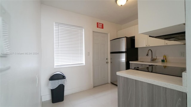 kitchen with baseboards, light countertops, a sink, and freestanding refrigerator