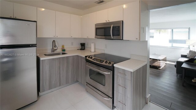 kitchen with sink, white cabinets, light hardwood / wood-style flooring, and stainless steel appliances