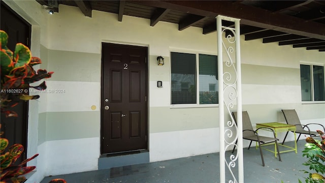 doorway to property with a porch and stucco siding