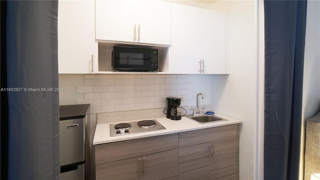 kitchen with white cabinetry, sink, backsplash, and white electric stovetop