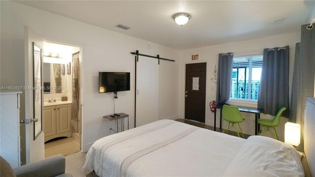 bedroom featuring ensuite bathroom, light colored carpet, and sink