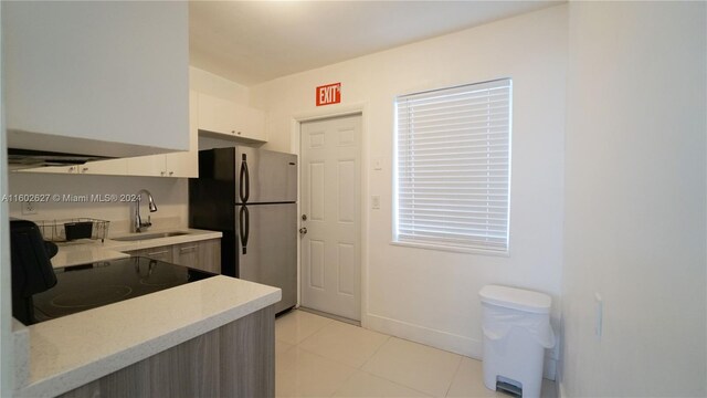 kitchen with stainless steel fridge, sink, light tile flooring, and range