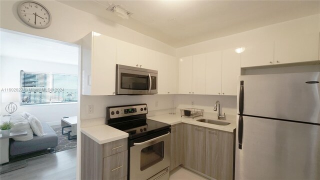 kitchen featuring sink, hardwood / wood-style flooring, white cabinetry, and appliances with stainless steel finishes