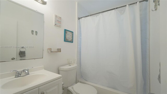 full bathroom featuring shower / bath combination with curtain, vanity, and toilet