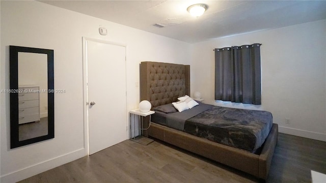 bedroom with dark wood-style flooring, visible vents, and baseboards