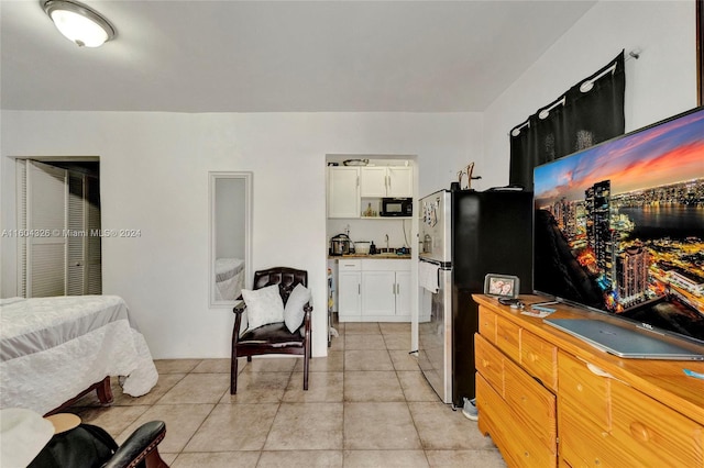 bedroom with light tile patterned flooring and stainless steel fridge