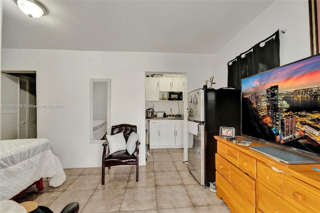 kitchen with stainless steel refrigerator, white cabinetry, sink, and light tile patterned floors