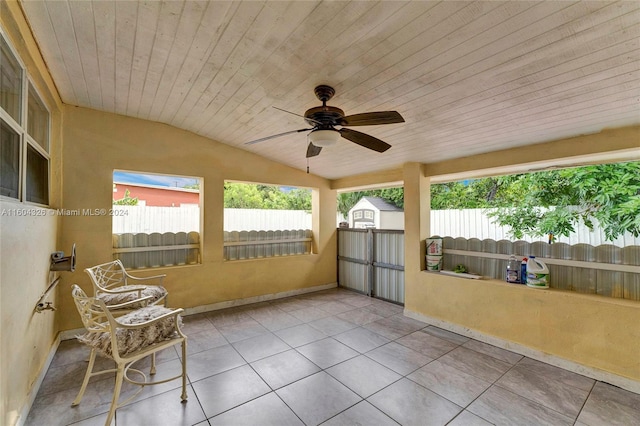 unfurnished sunroom featuring ceiling fan, lofted ceiling, a healthy amount of sunlight, and wooden ceiling