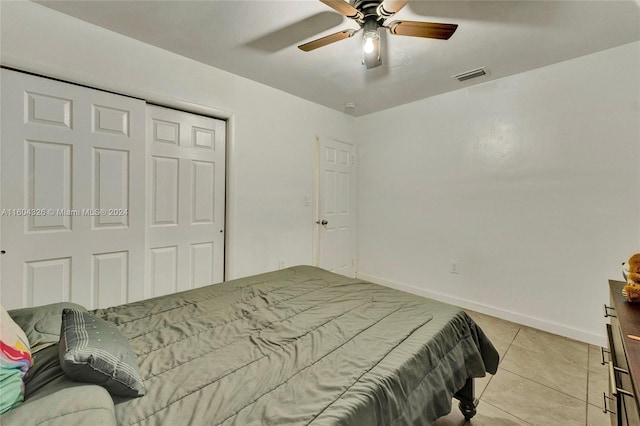 tiled bedroom featuring ceiling fan and a closet