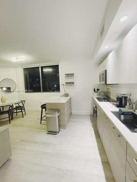 kitchen with black electric stovetop, white cabinetry, and sink