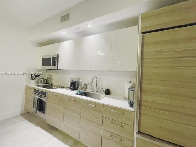 kitchen featuring white cabinets, stainless steel appliances, and sink