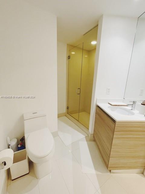 bathroom featuring tile patterned floors, a shower with door, vanity, and toilet