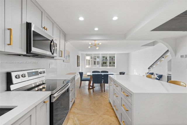 kitchen featuring white cabinetry, stainless steel appliances, decorative light fixtures, and an inviting chandelier