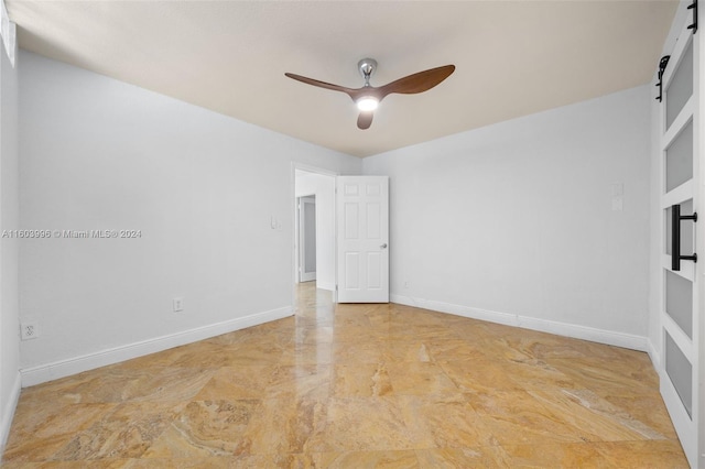 empty room with ceiling fan and a barn door