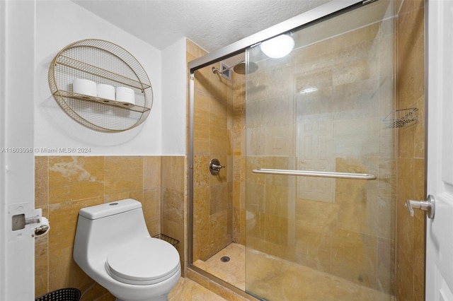 bathroom featuring a shower with door, tile walls, a textured ceiling, and toilet