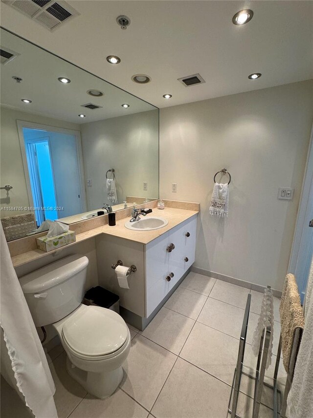 bathroom with tile floors, large vanity, and toilet