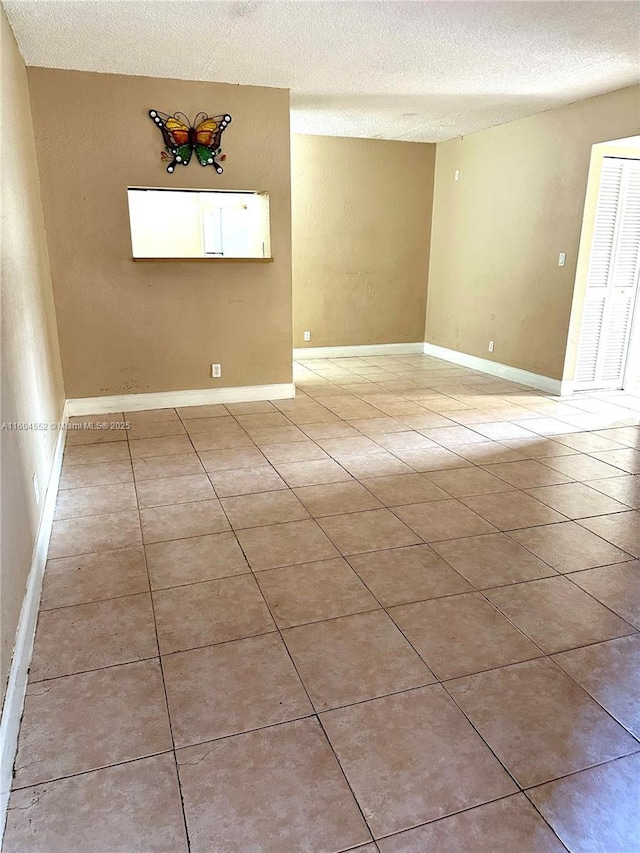 empty room featuring light tile patterned flooring and a textured ceiling