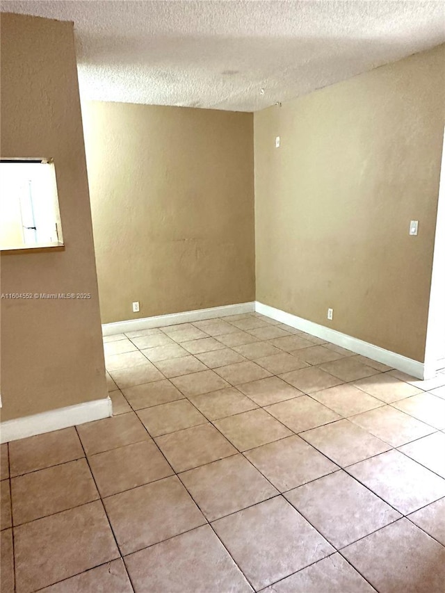 tiled empty room with a textured ceiling