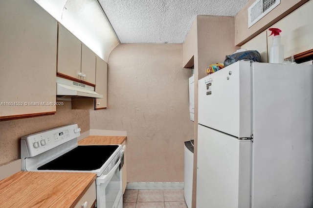 kitchen with light tile patterned flooring, white appliances, and a textured ceiling