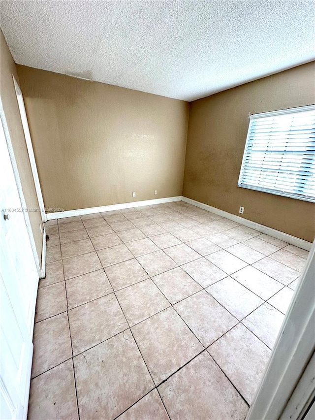 empty room featuring light tile patterned floors and a textured ceiling