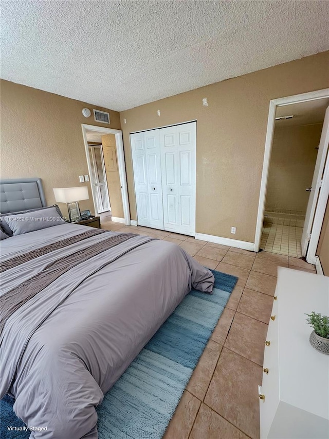 bedroom featuring a closet, light tile patterned floors, and a textured ceiling