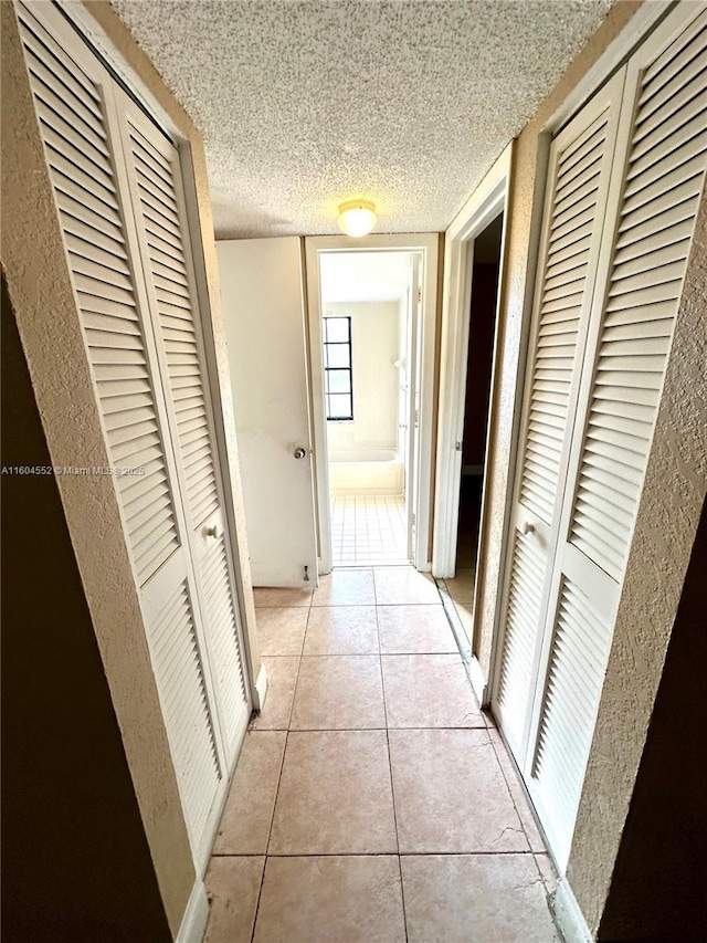 hallway with light tile patterned floors and a textured ceiling