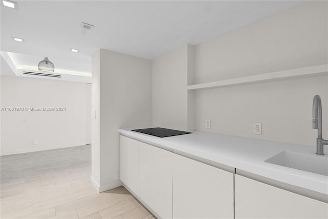 bar with white cabinetry, sink, and light wood-type flooring