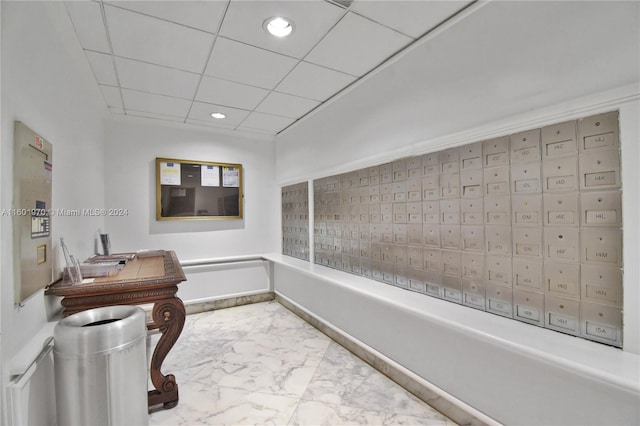 hall with a drop ceiling and light tile patterned floors