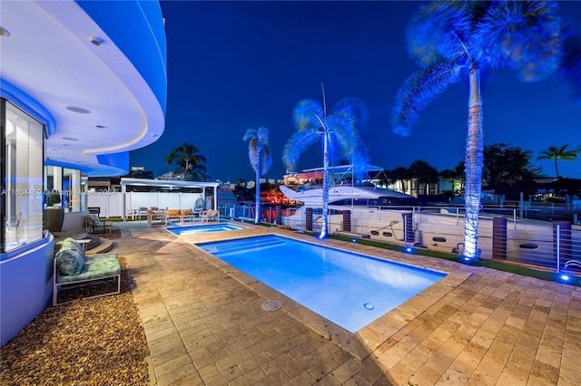 3344 NE 167th St, North Miami Beach, FL 33160 - pool at night with a patio area, an in-ground hot tub, and a fenced backyard