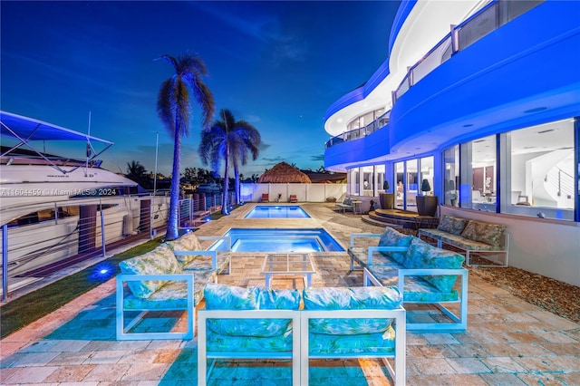 pool at dusk with an in ground hot tub and a patio area