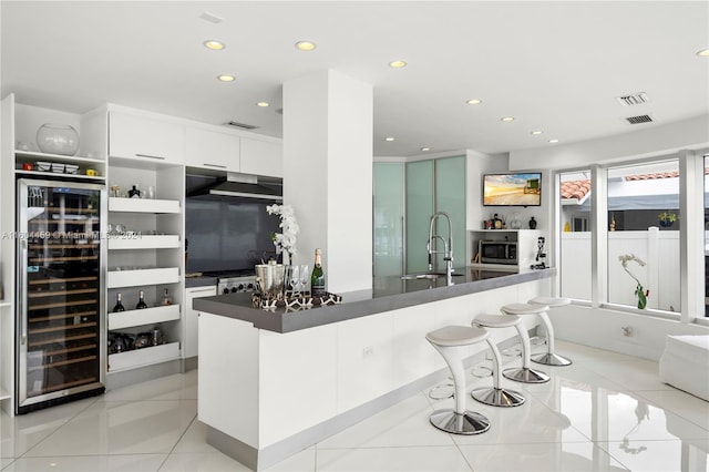 kitchen with beverage cooler, sink, stainless steel appliances, white cabinets, and light tile patterned floors