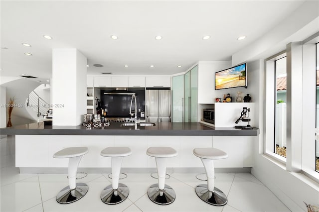 3344 NE 167th St, North Miami Beach, FL 33160 - kitchen with stainless steel appliances, dark countertops, a peninsula, a breakfast bar area, and a sink