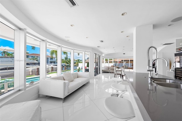 living room featuring light tile patterned flooring, plenty of natural light, and sink