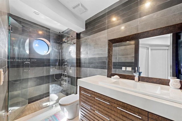 bathroom with an enclosed shower, vanity, tile walls, and toilet