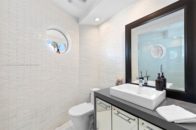 bathroom with tile patterned floors, toilet, vanity, and brick wall